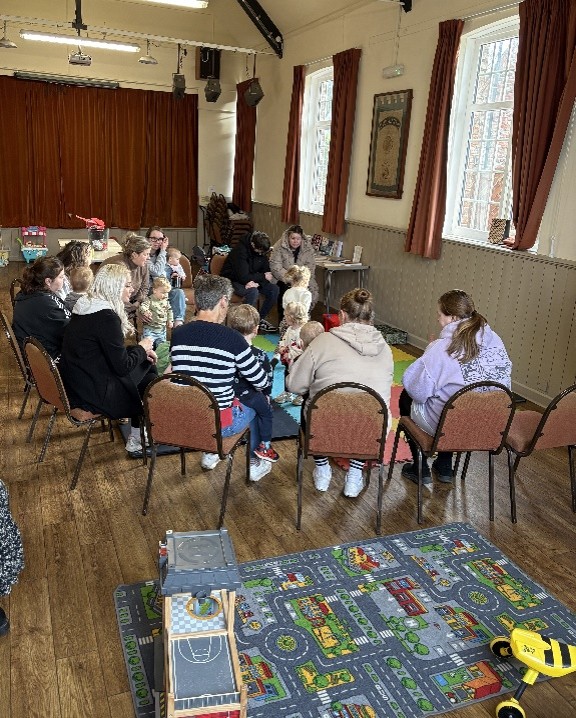 a group of parents/carers in a church hall with children