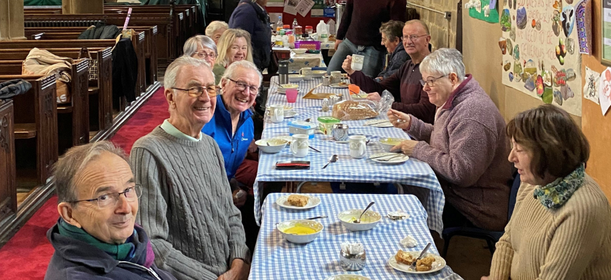 people sat round tables in a church eating lunch