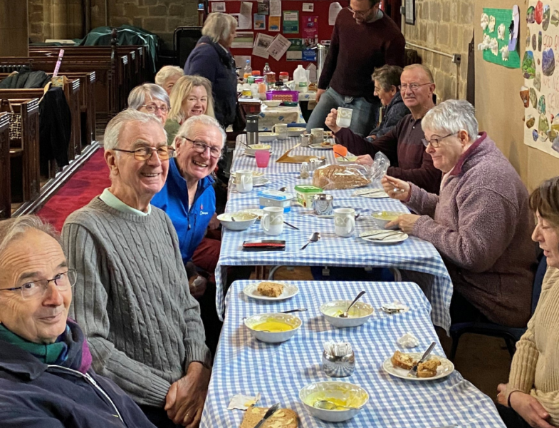 people sat round tables in a church eating lunch