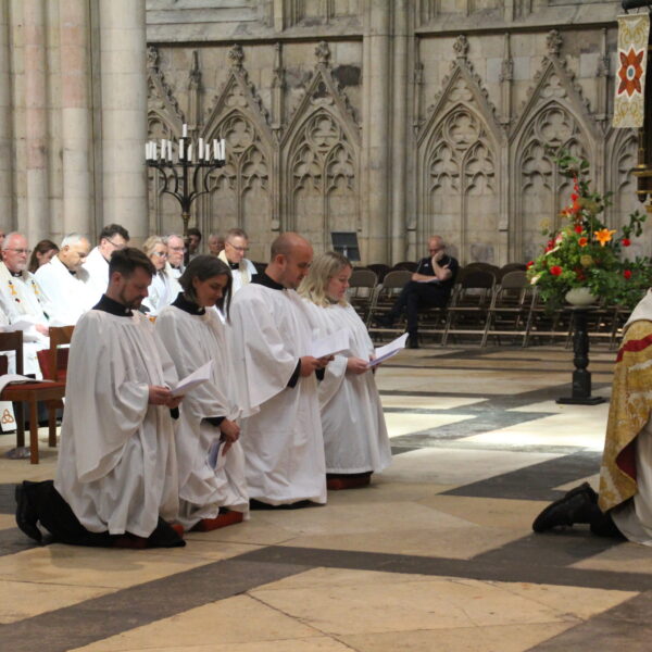 deacon ordination service in york minster. four deacons and the archbishop of york, all kneeling.