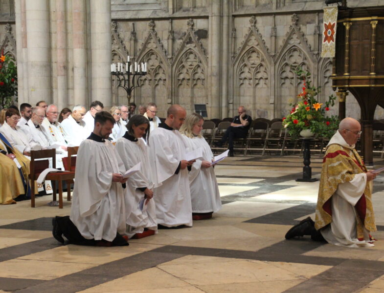 deacon ordination service in york minster. four deacons and the archbishop of york, all kneeling.